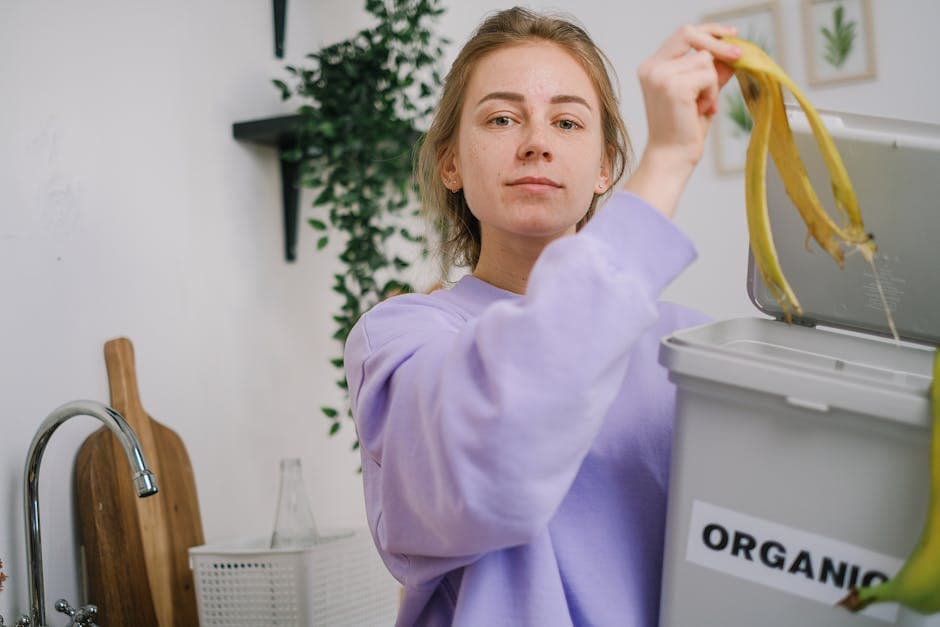 Woman composting organic kitchen waste in home composting system